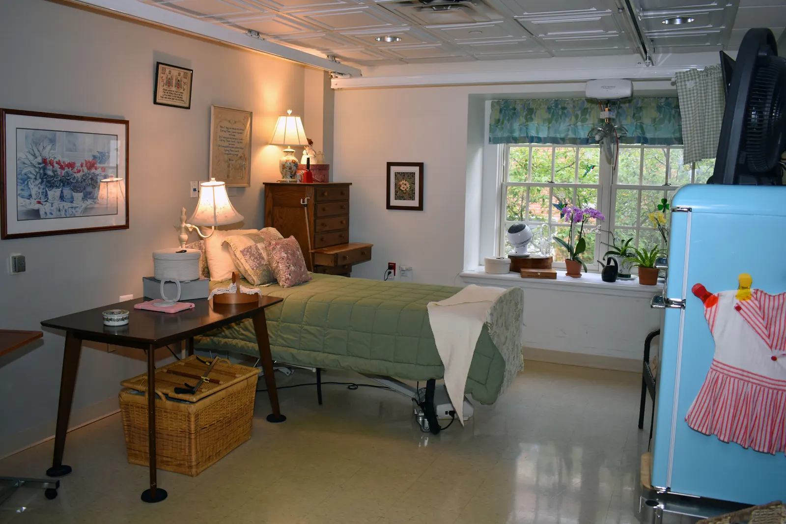 Resident room at The Beechwood Home with a quilted bed, framed artwork, family keepsakes, and a sunny window