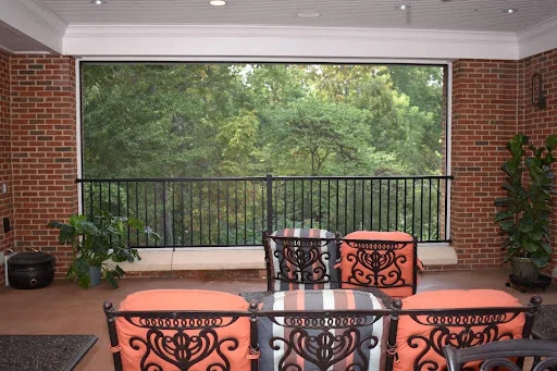 Screened porch with patio seating overlooking the wooded grounds
